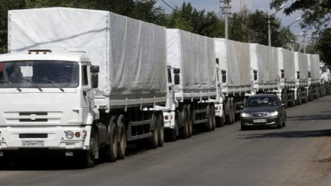 A car drives past trucks of a Russian convoy carrying humanitarian aid for Ukraine near a Russia-Ukraine border crossing point in Rostov Region